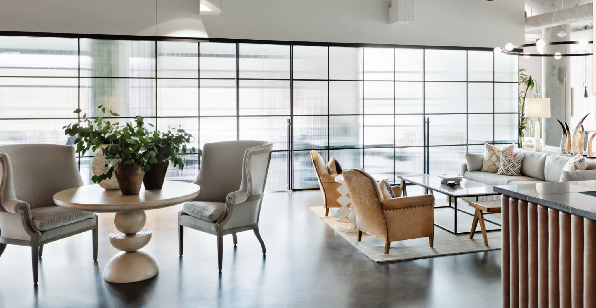 Bond Collective East Austin elegant lounge with floor-to-ceiling windows, pedestal table, wingback chairs, and neutral tones