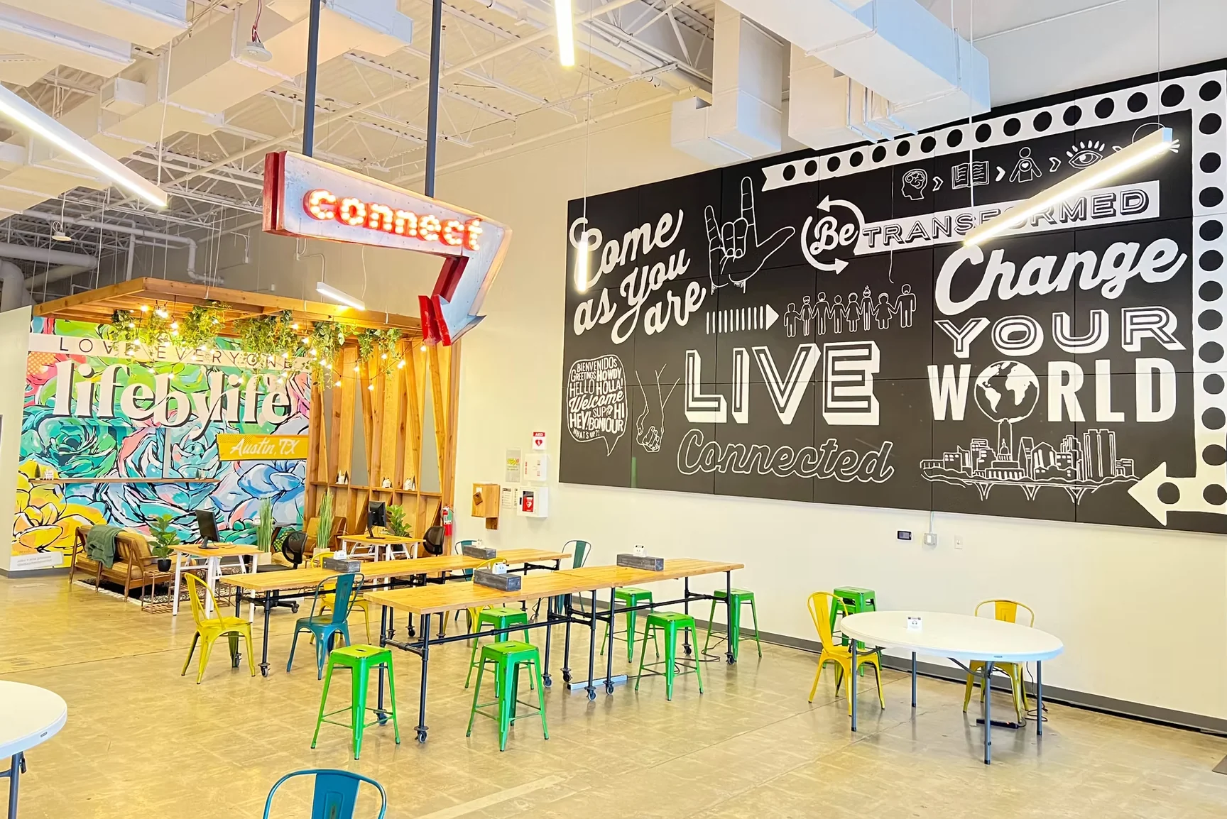 Dwell Coworking in South Austin with vibrant murals, Connect neon sign, colorful metal stools, and inspirational wall art