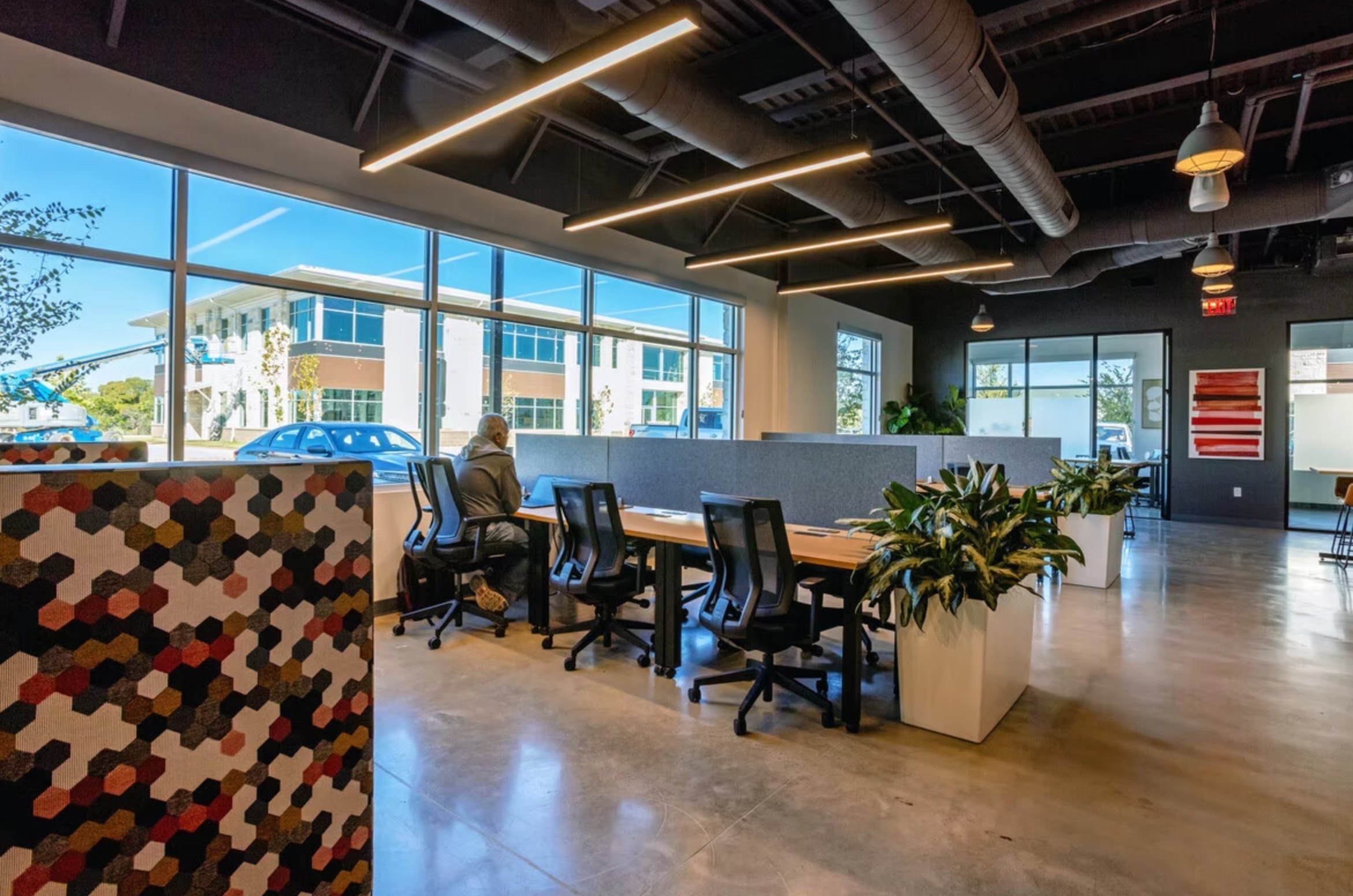 FUSE Workspace Four Points with modern open-plan coworking area, hexagonal desk panel, large windows, and plants
