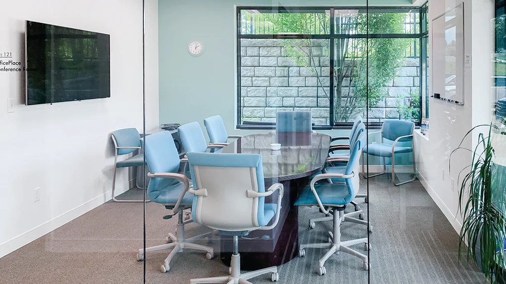 OfficePlace Middletown - glass-walled conference room with blue chairs and garden courtyard view