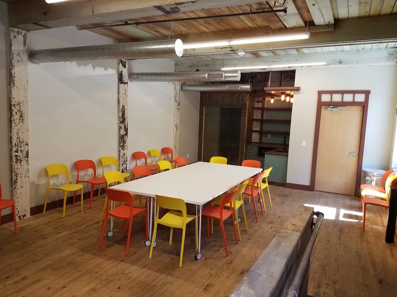 Mad River Office Lofts Winsted - industrial meeting space with orange and yellow chairs and exposed ceiling
