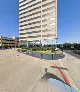 Common Desk Lowest Greenville exterior showing a modern high-rise office building with landscaped entrance, trees, and colorful ground-level sculptures on a sunny day