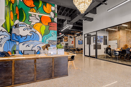 Workspace Collective Daytona Beach colorful mural reception with ocean artwork, chandelier, and glass-walled meeting room