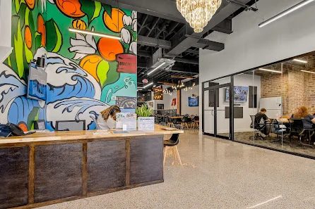 Workspace Collective Daytona Beach colorful mural reception with ocean artwork, chandelier, and glass-walled meeting room
