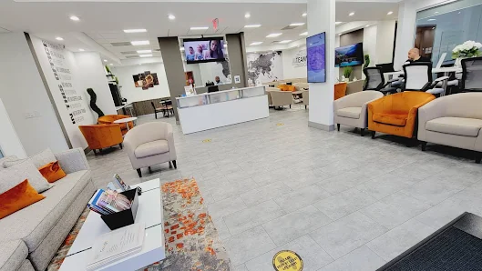 Office Hub 56 modern lobby with white reception desk, orange accent pillows, and gray wingback chairs