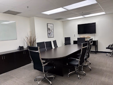 Execu-Suites conference room with oval table, black executive chairs, and wall-mounted TV