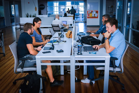 CoWork Annex open shared desk area with people working on laptops at white tables in bright natural light
