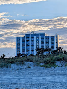 Cocoa Beach Office beachfront high-rise building viewed from sand dunes at dusk with dramatic cloudy sky