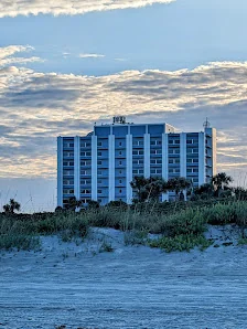 Cocoa Beach Office beachfront high-rise building viewed from sand dunes at dusk with dramatic cloudy sky