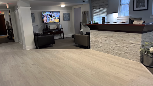 Execu-Suites lobby with light hardwood floors, stone-clad reception counter, and dark leather armchairs