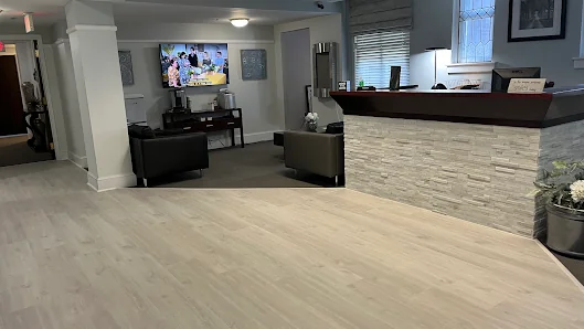Execu-Suites lobby with light hardwood floors, stone-clad reception counter, and dark leather armchairs