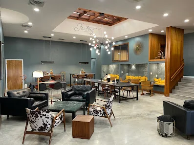 Foundry Coworking stylish lounge with blue-gray walls, cowhide accent chairs, leather seating, and sputnik chandelier