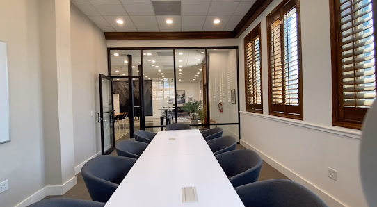 Ripple Coworking Daytona Beach long white conference table with dark upholstered chairs and glass-walled offices