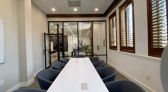 Ripple Coworking Daytona Beach long white conference table with dark upholstered chairs and glass-walled offices