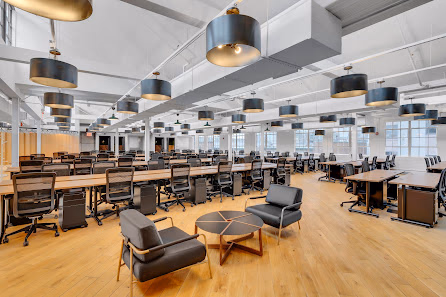 The Mark Manhattan Laundry massive open-plan coworking floor with rows of desks, large drum pendant lights, and hardwood floors