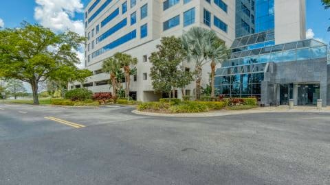 HQ Sand Lake modern multi-story glass office building with palm trees and landscaped circular driveway