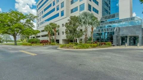 HQ Sand Lake modern multi-story glass office building with palm trees and landscaped circular driveway