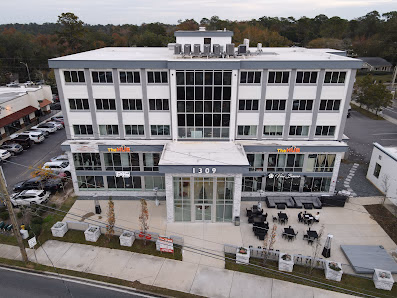 The Hub Tallahassee aerial view of modern four-story white building with glass facade and outdoor patio seating