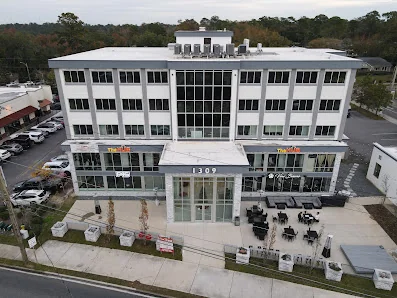 The Hub Tallahassee aerial view of modern four-story white building with glass facade and outdoor patio seating
