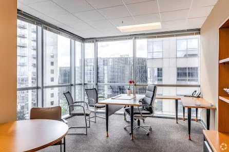 YourOffice Downtown Orlando corner private office with floor-to-ceiling windows, city views, desk with chairs, and round meeting table