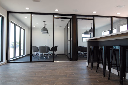 Ripple Coworking Flagler Beach glass-walled conference room with gray chairs, bar-height counter with black stools, and industrial pendant lights