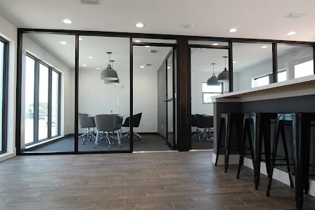 Ripple Coworking Flagler Beach glass-walled conference room with gray chairs, bar-height counter with black stools, and industrial pendant lights