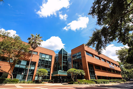Florida Office Centers large three-story brick and glass office building surrounded by mature trees under blue sky