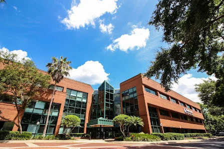 Florida Office Centers large three-story brick and glass office building surrounded by mature trees under blue sky