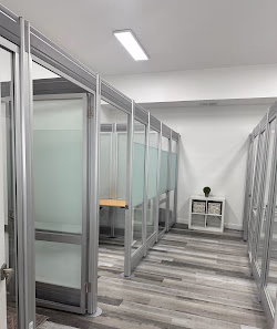 Brevard Workspace hallway of glass-partitioned private office pods with aluminum frames and minimalist white interior