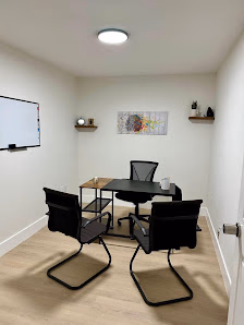 Coworkers Zone small meeting room with black table and chairs, wall-mounted TV, brain artwork, and light wood flooring