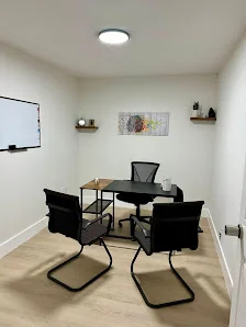 Coworkers Zone small meeting room with black table and chairs, wall-mounted TV, brain artwork, and light wood flooring