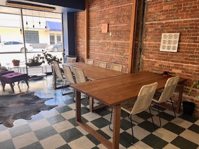 Office Share Palatka rustic exposed brick interior with wooden conference table, woven chairs, and green-and-white checkered floor