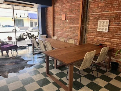 Office Share Palatka rustic exposed brick interior with wooden conference table, woven chairs, and green-and-white checkered floor
