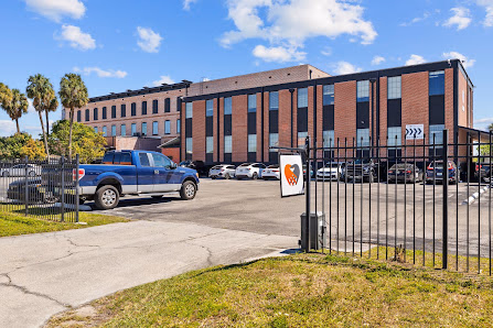 CoWorkTampa exterior brick building with gated parking lot and palm trees