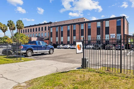CoWorkTampa exterior brick building with gated parking lot and palm trees