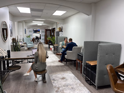 Share Space Coworking cozy lounge with gray booth seating, people chatting, and arched ceiling details