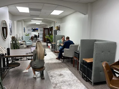 Share Space Coworking cozy lounge with gray booth seating, people chatting, and arched ceiling details