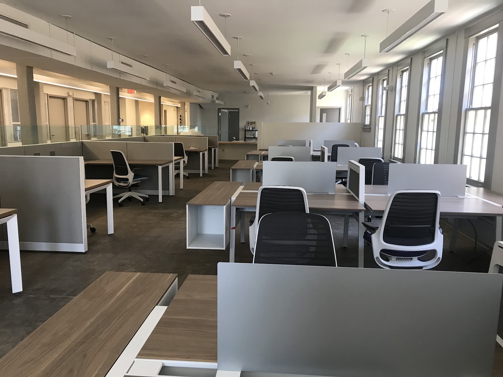 Parish Hall Offices open floor with rows of modern cubicle desks, gray partitions, mesh office chairs, overhead fluorescent lights, and tall windows