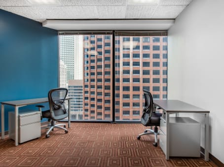 Regus St Charles and Poydras private office with teal accent wall, two black desks, mesh chairs, diamond carpet, and high-rise window view