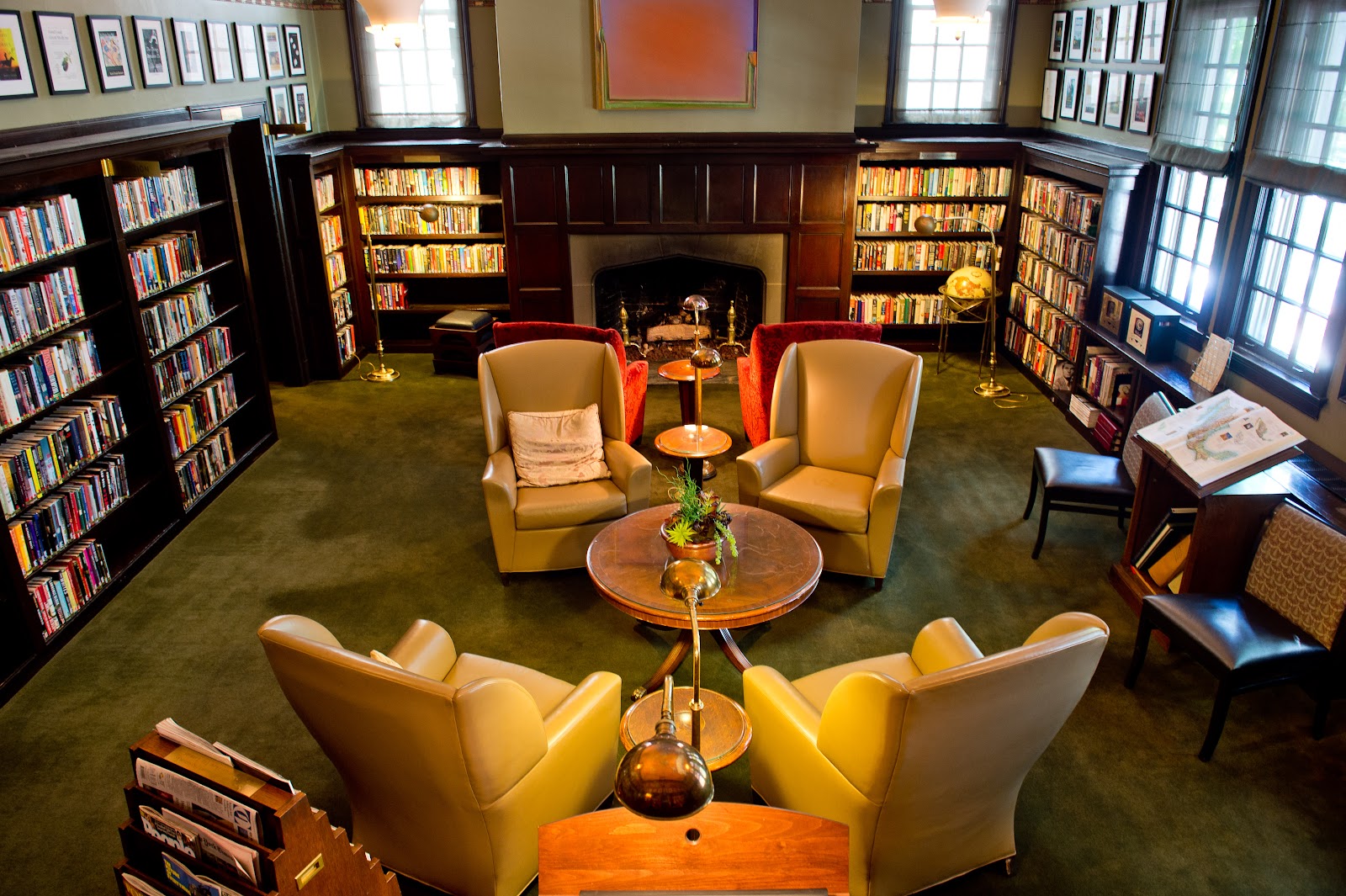 University Club of Portland grand library with dark wood bookshelves, fireplace, olive-green carpet, tan leather wingback chairs, copper side tables, and globe lamp