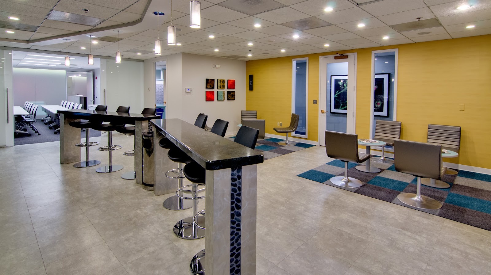 AdvantEdge Workspaces modern lounge with chrome stools, black granite bar, yellow accent wall and teal carpet