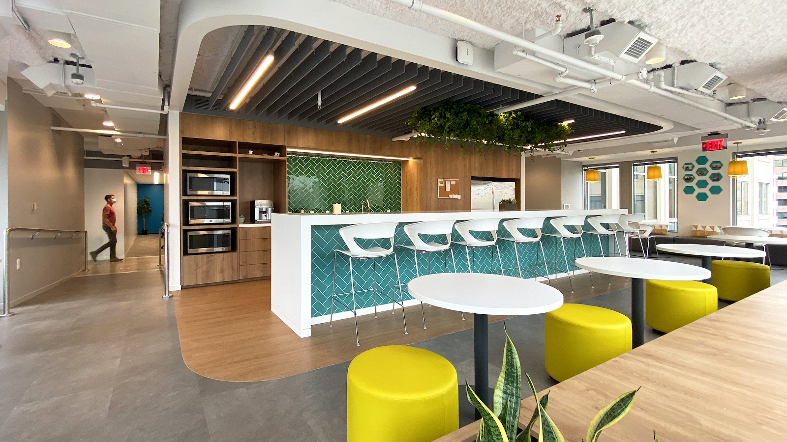 Open Gov Hub kitchen and cafe area with teal herringbone tile, yellow ottoman stools, and modern bar seating