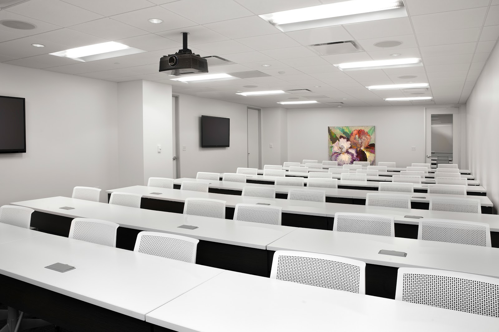 AdvantEdge Workspaces Thomas Jefferson training room with rows of white desks, projector, and floral painting