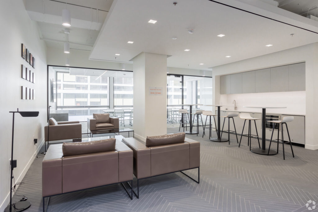 Symbiosis modern lounge with mauve leather sofas, herringbone gray flooring, white kitchen bar area, and city views