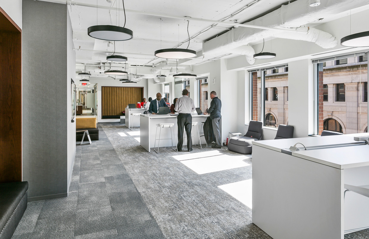 District Offices Capitol Hill open workspace with professionals at standing-height tables, circular pendant lights, and city views