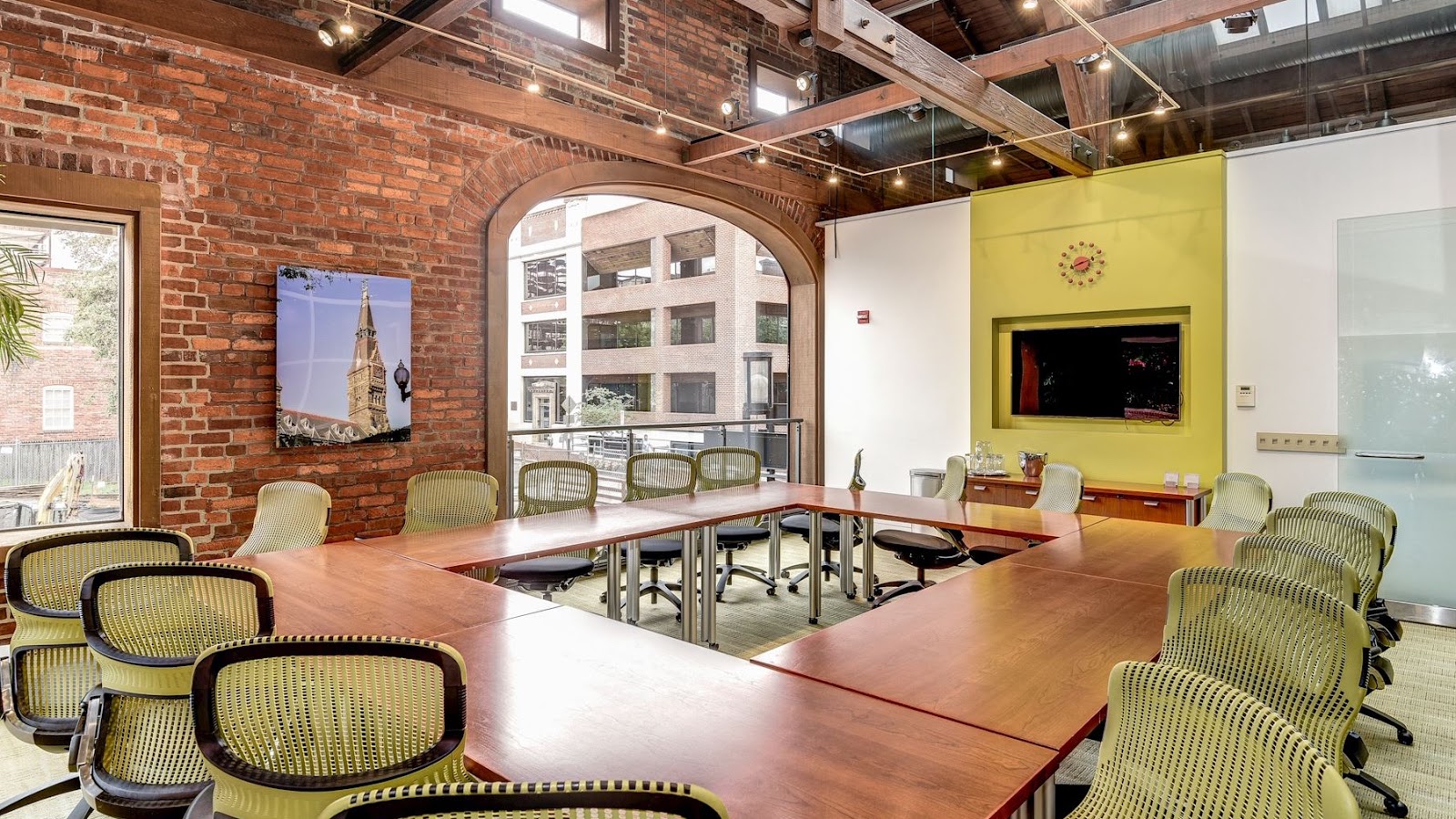 Carr Workplaces Georgetown exposed brick conference room with arched window, cherry wood U-shaped table, and olive green Herman Miller chairs