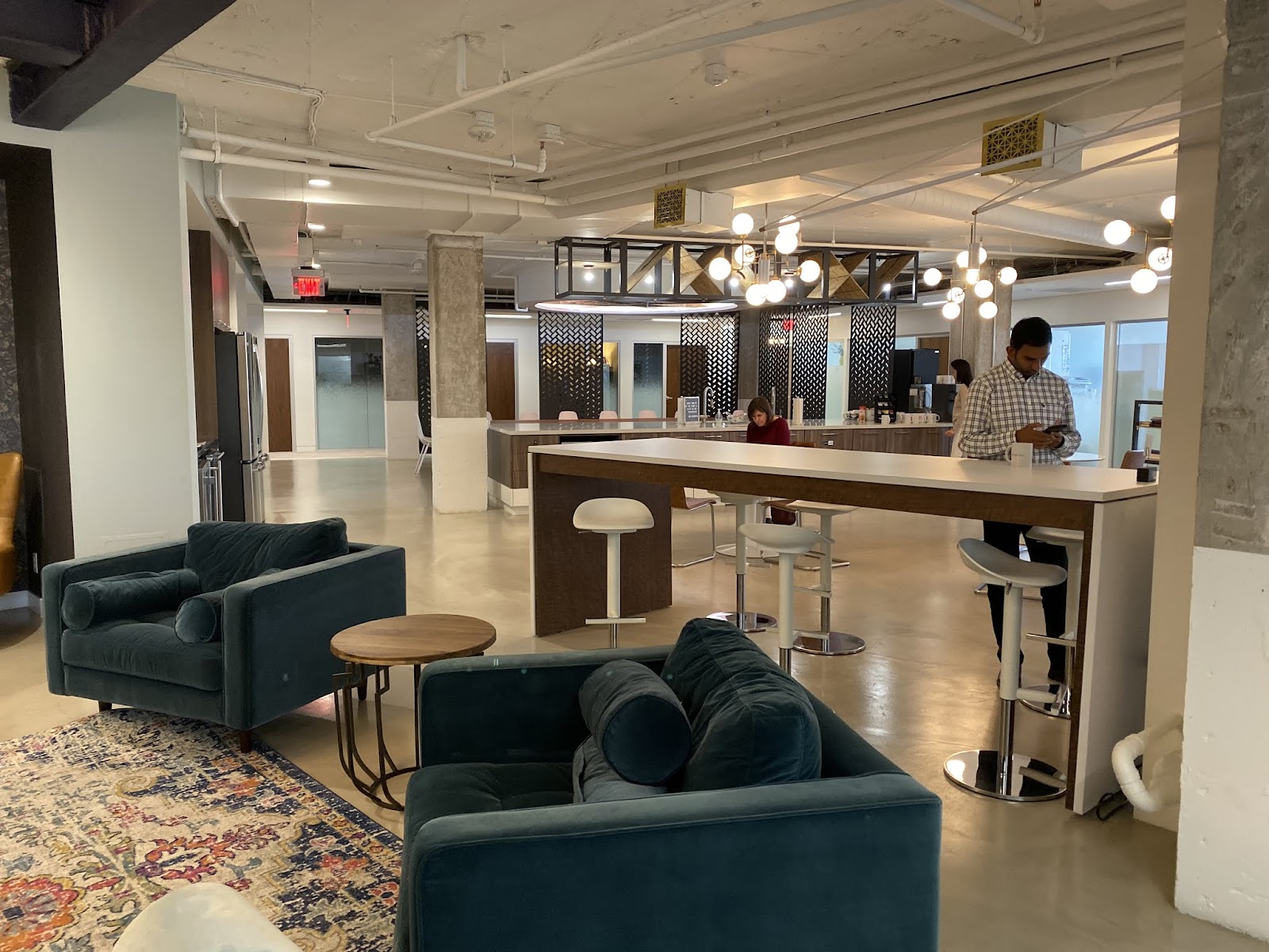Metro Offices Dupont Circle lounge with teal velvet sofas, oriental rug, bar counter and industrial-chic decor