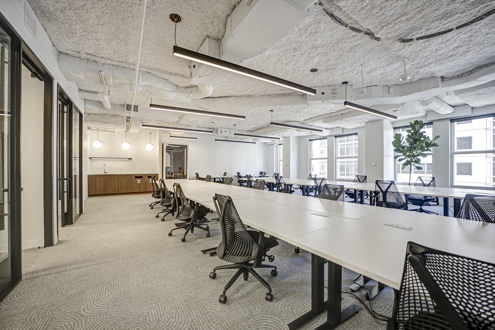 The Square Bowen Building open office with long white desks, mesh chairs, linear LED fixtures, and textured carpet