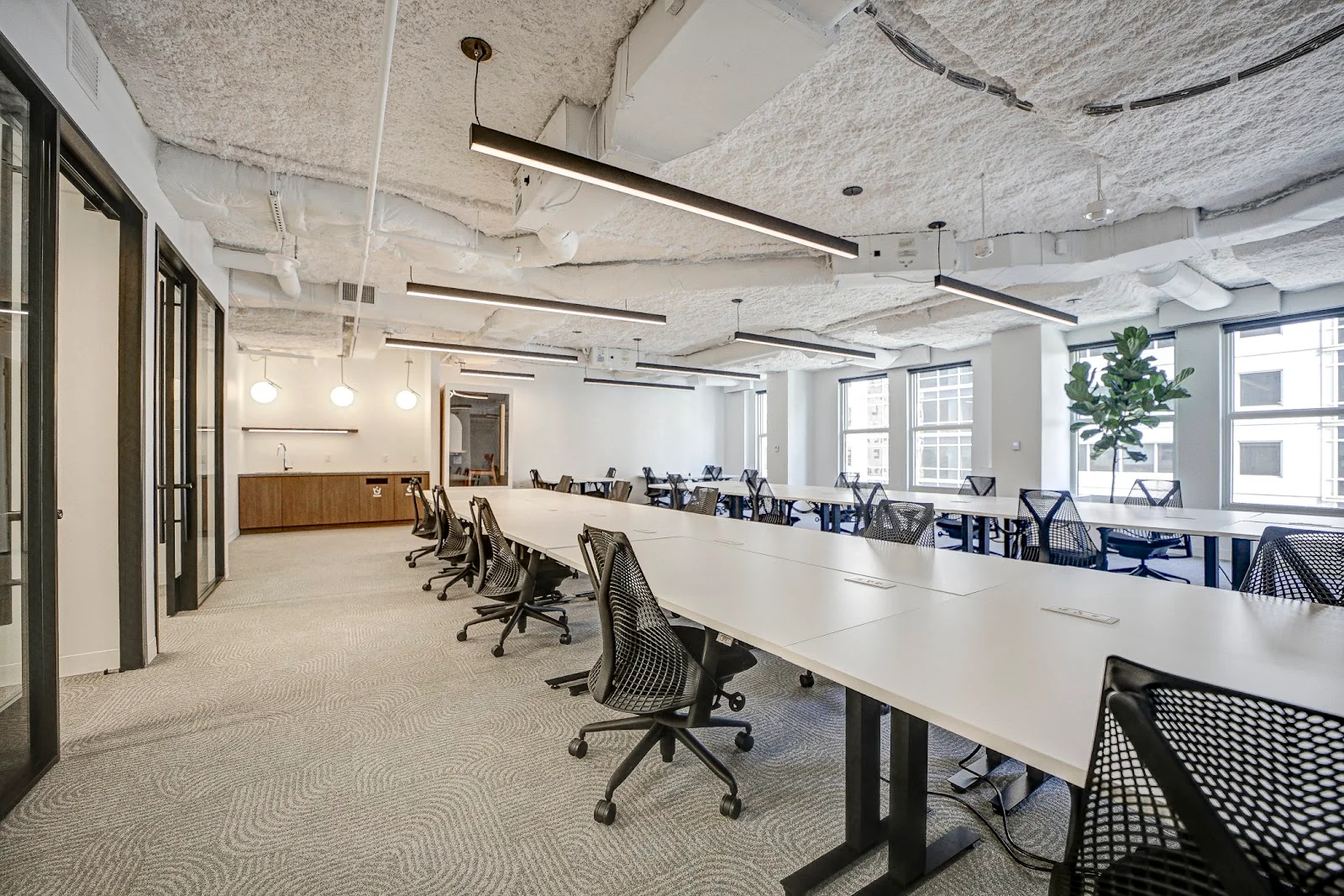 The Square Bowen Building open office with long white desks, mesh chairs, linear LED fixtures, and textured carpet