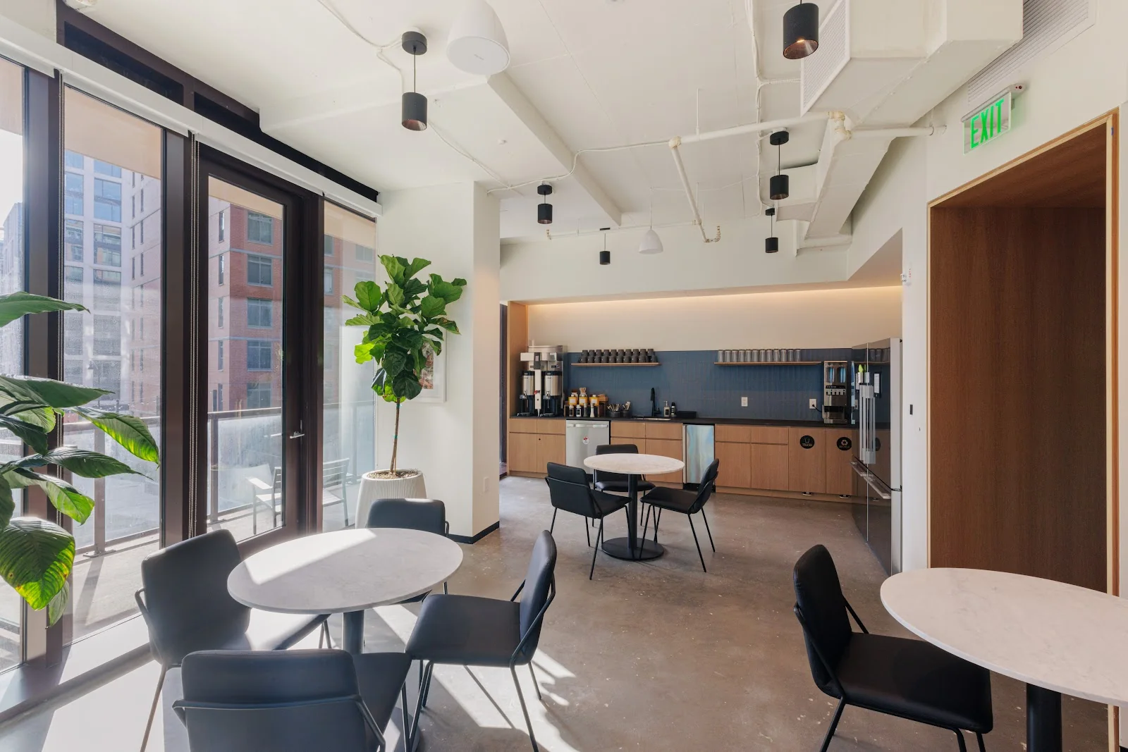 Industrious New Jersey Ave kitchen area with blue tile backsplash, marble cafe tables, fiddle leaf fig, and floor-to-ceiling windows